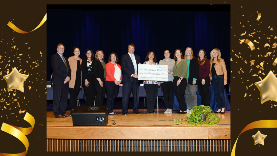 Group standing on stage with large check