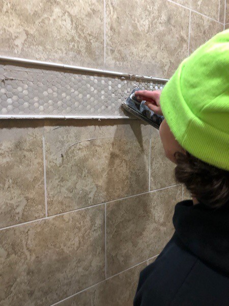 person grouting a tub surround