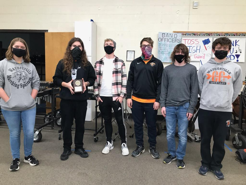 6 people wearing masks and one holding an award
